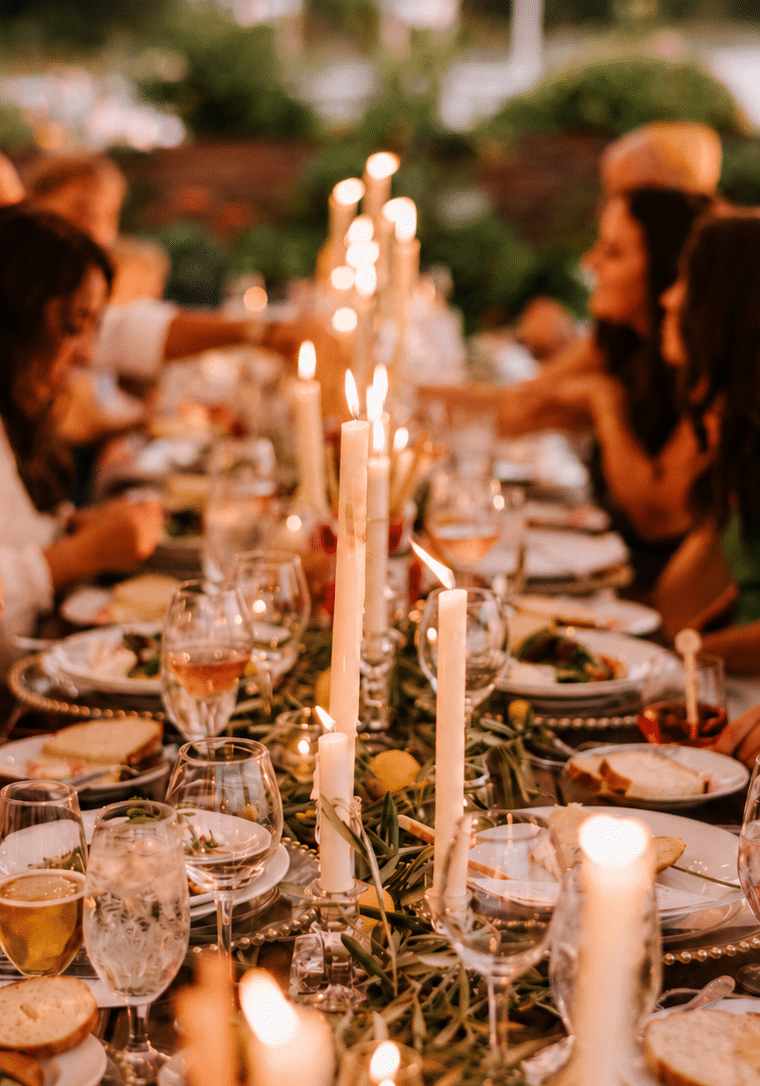 Guests smiling and connecting around a candlelit catered dinner table.
